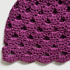 Close-up of a purple crocheted hat on a white background.