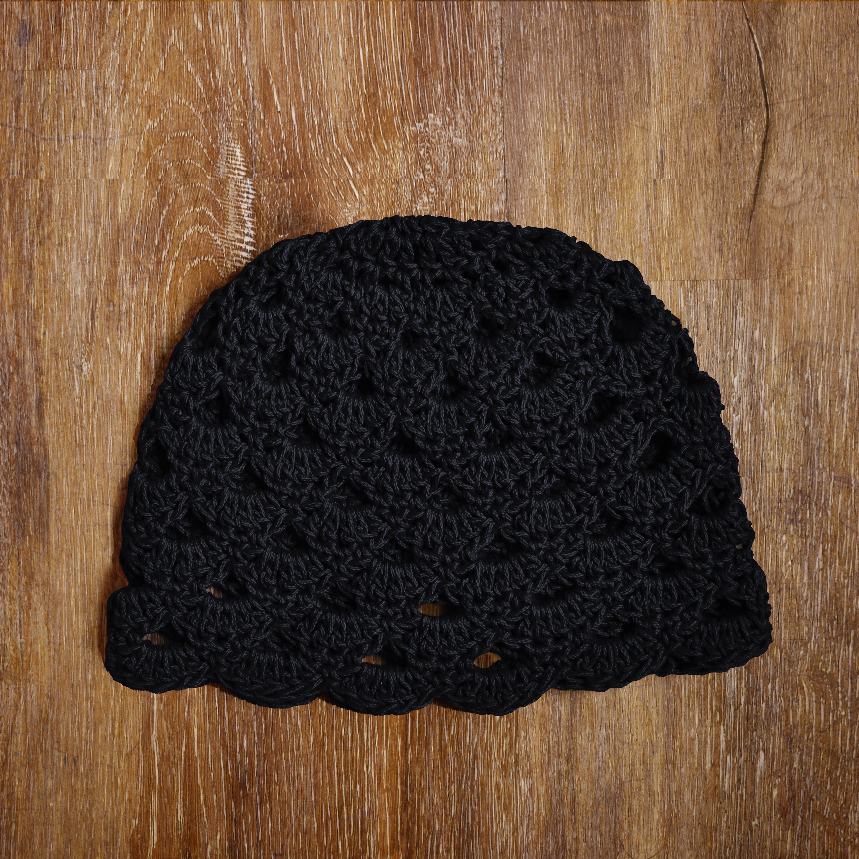 Black crocheted beanie on a wooden surface.