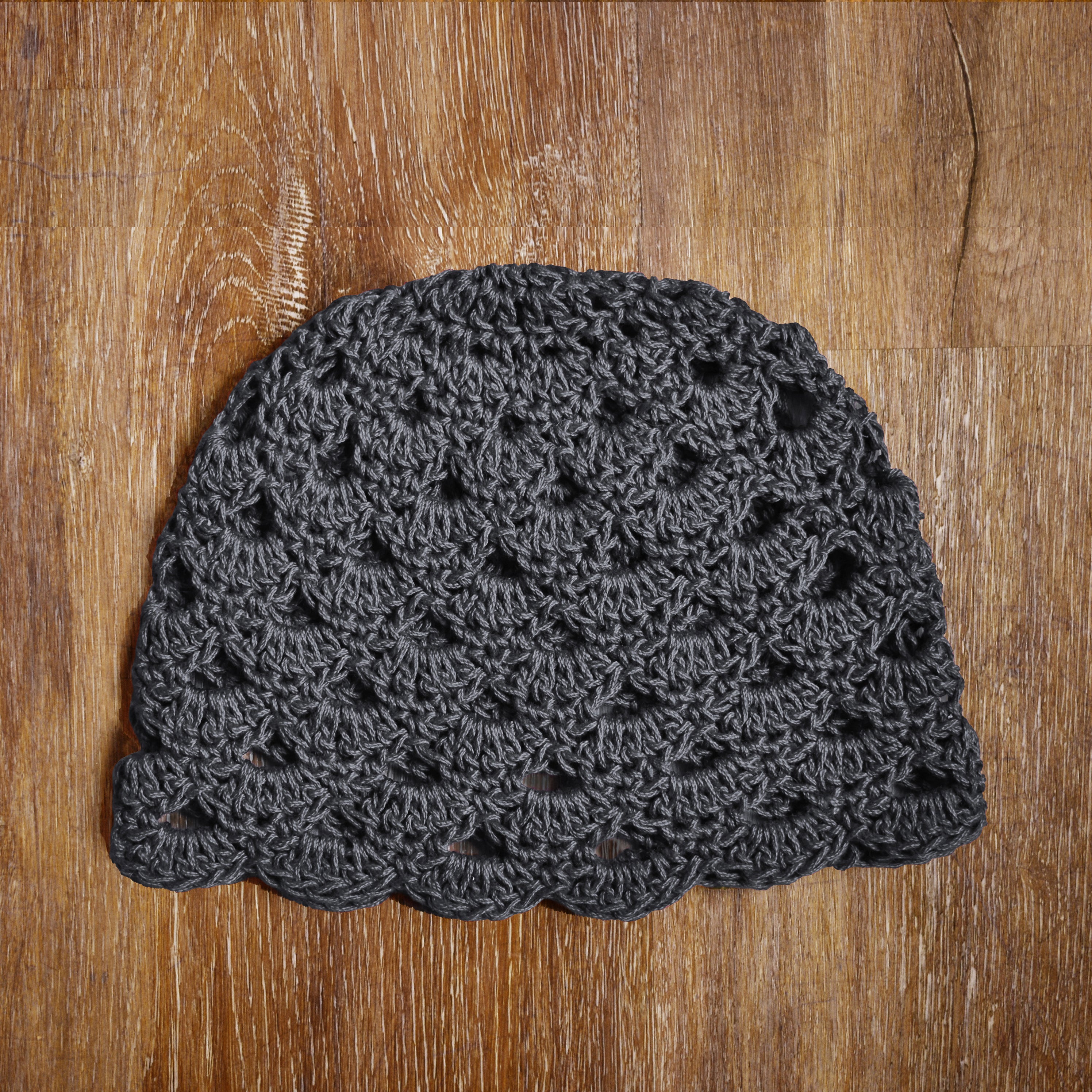 Dark gray crochet hat on a wooden surface.