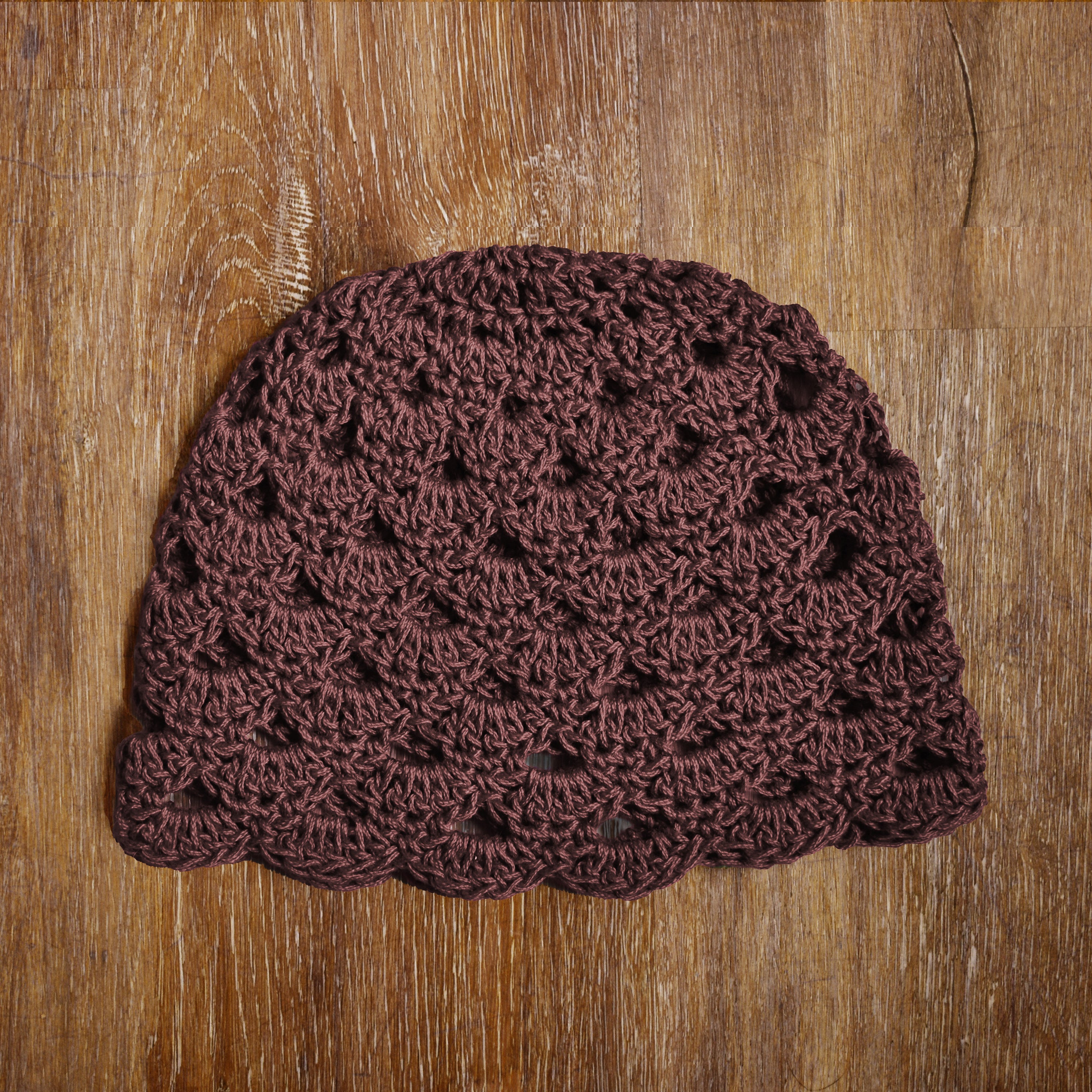 Brown crocheted beanie on a wooden surface.