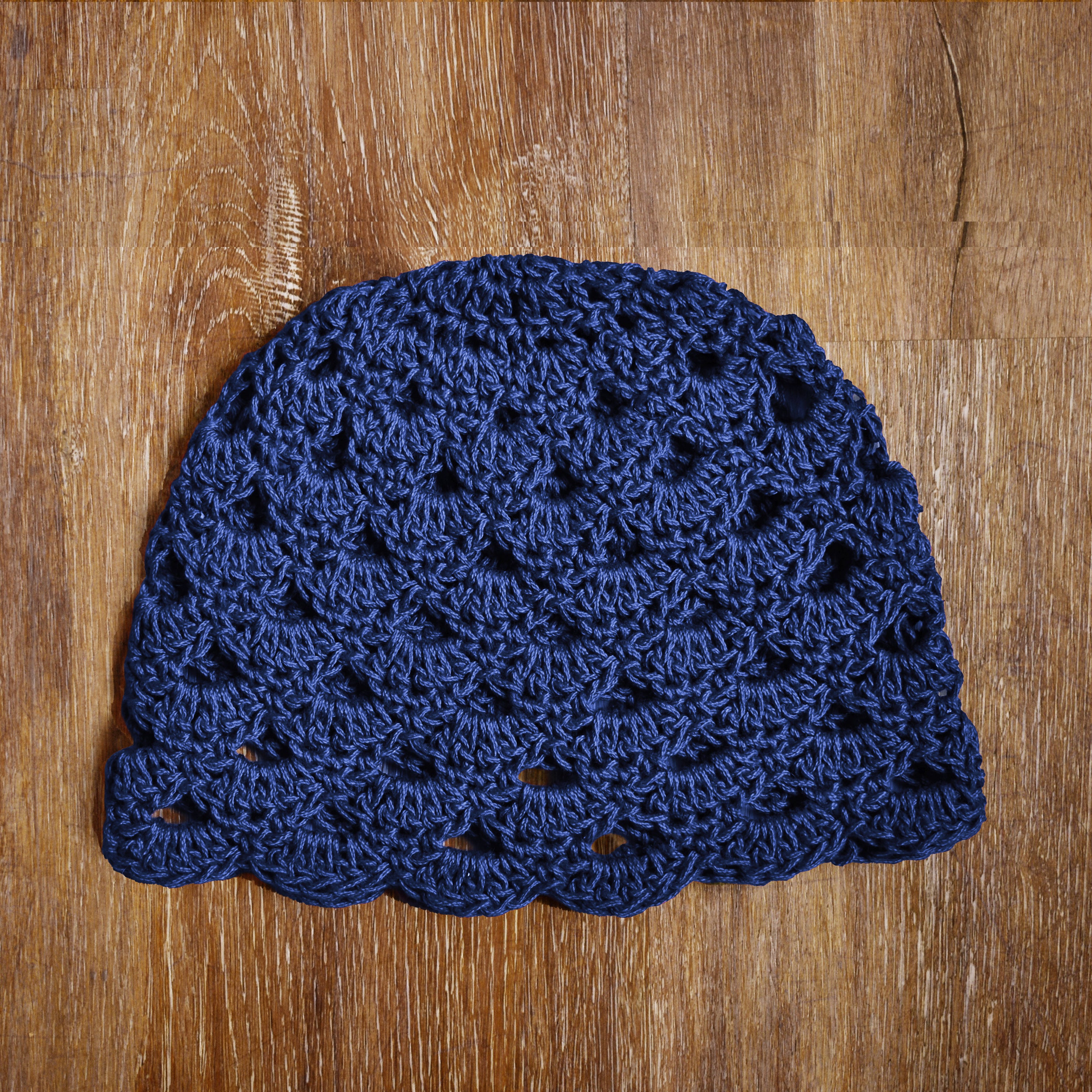Blue crocheted beanie on a wooden surface.
