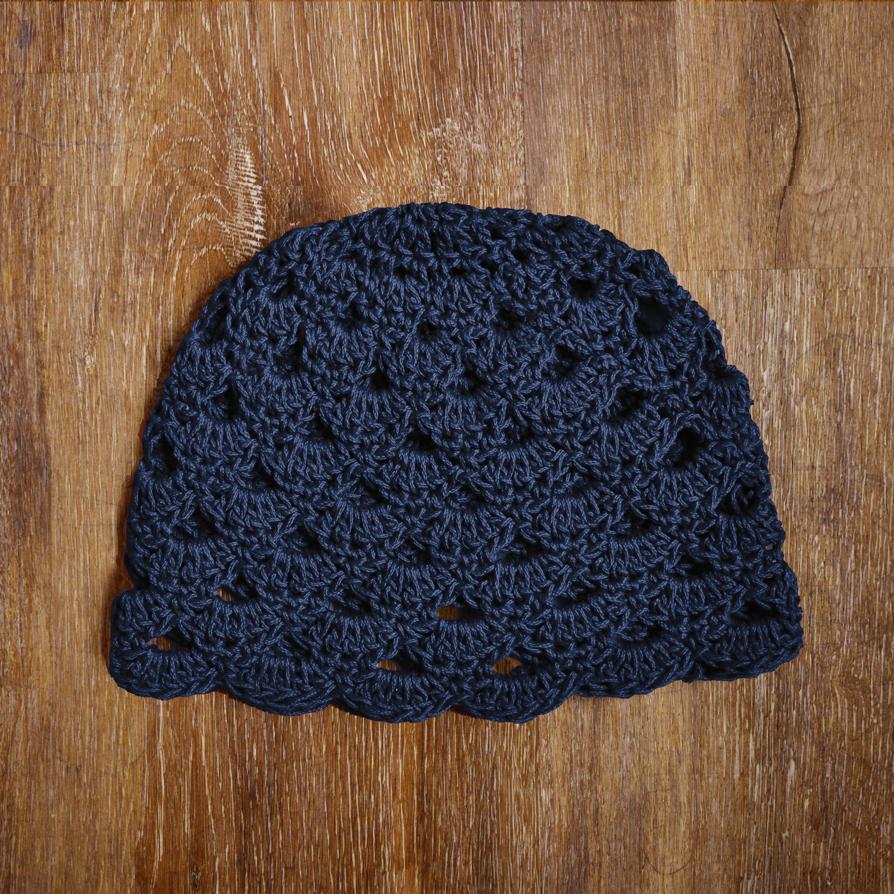 Dark blue crocheted beanie on a wooden surface.