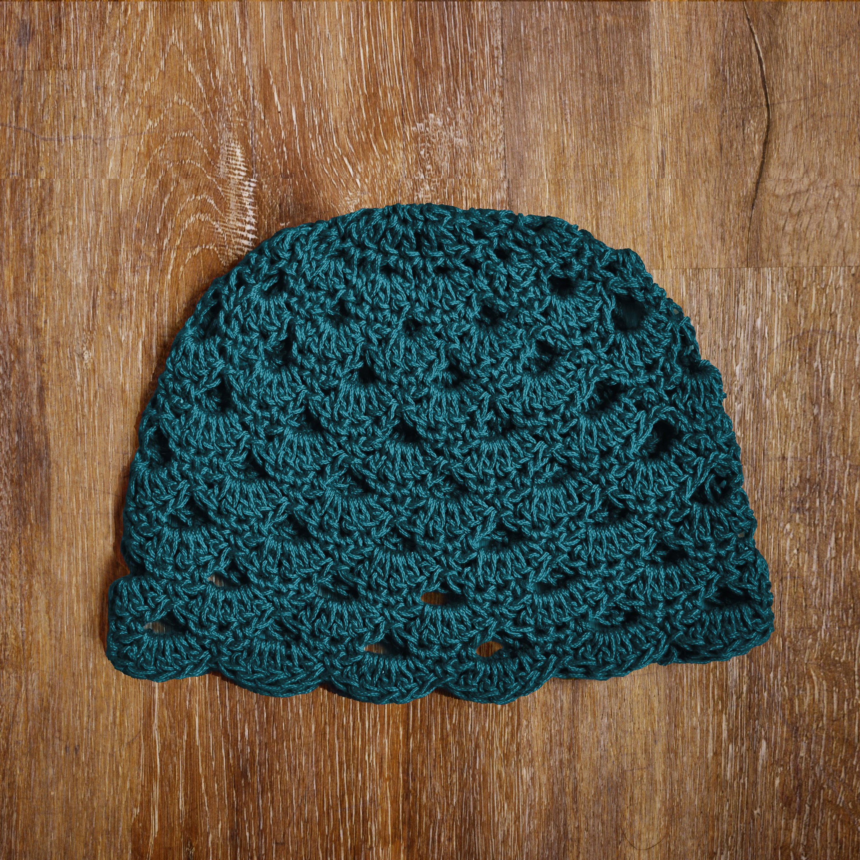 Teal crocheted hat on a wooden surface.