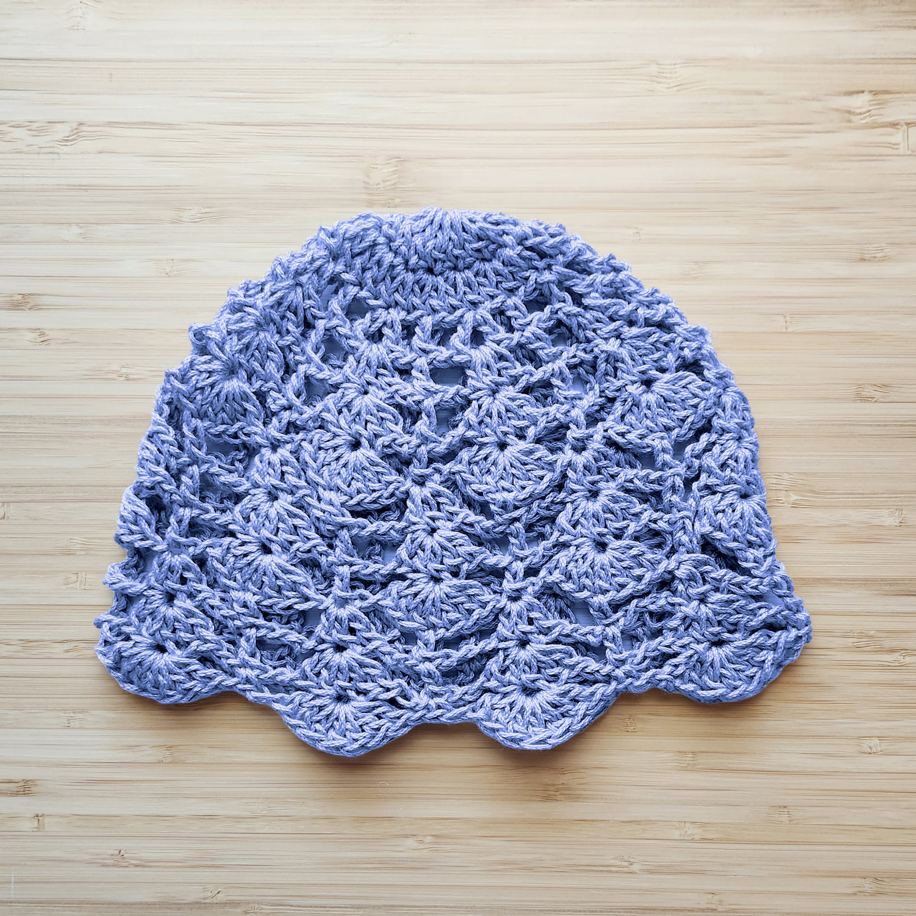 Baby blue crocheted boho lace hat on a wooden surface.