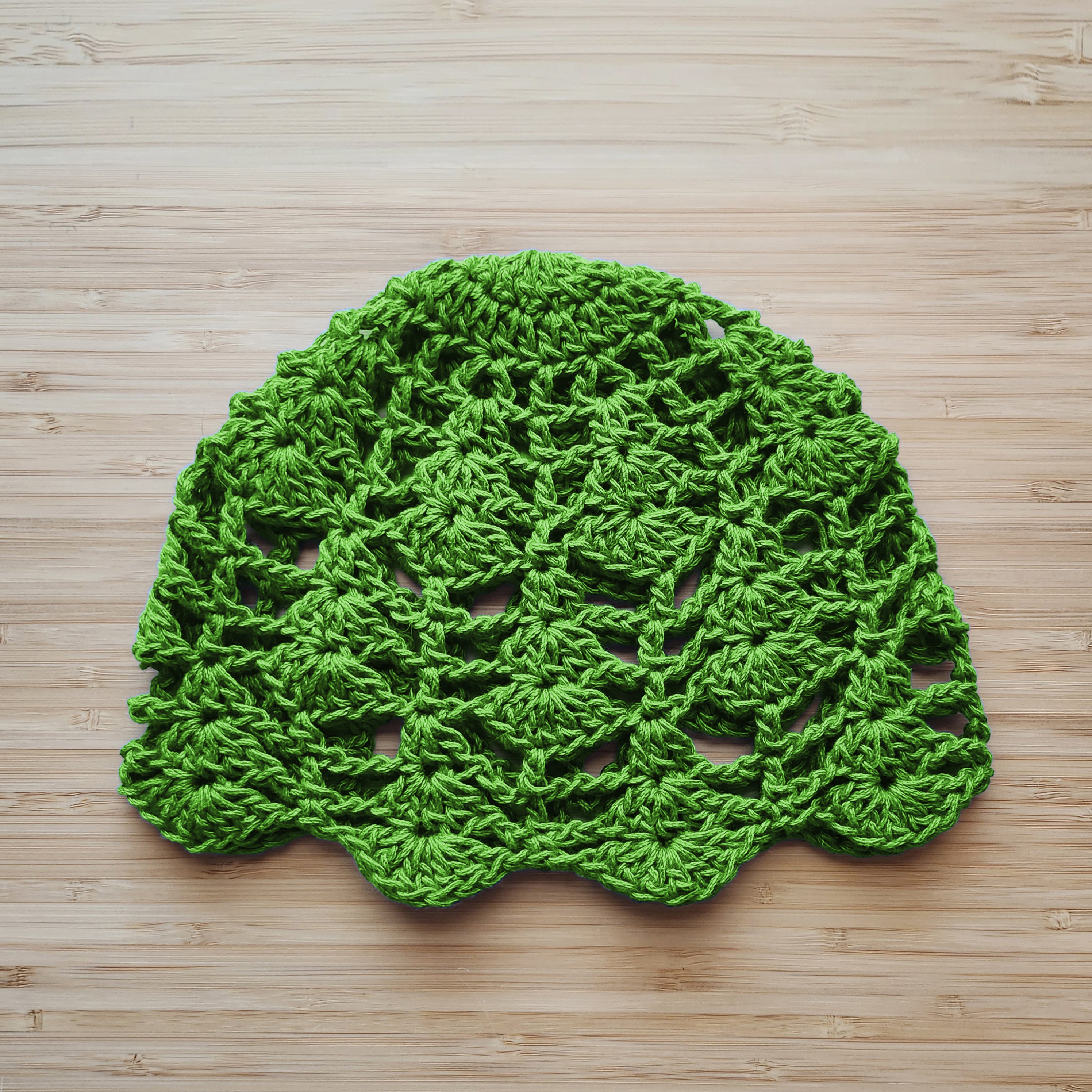 Green crocheted doily on a wooden surface.