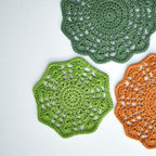 Three crocheted floral doilies in green and orange on a white background.