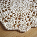 Close-up of a crocheted floral doily on a wooden surface.