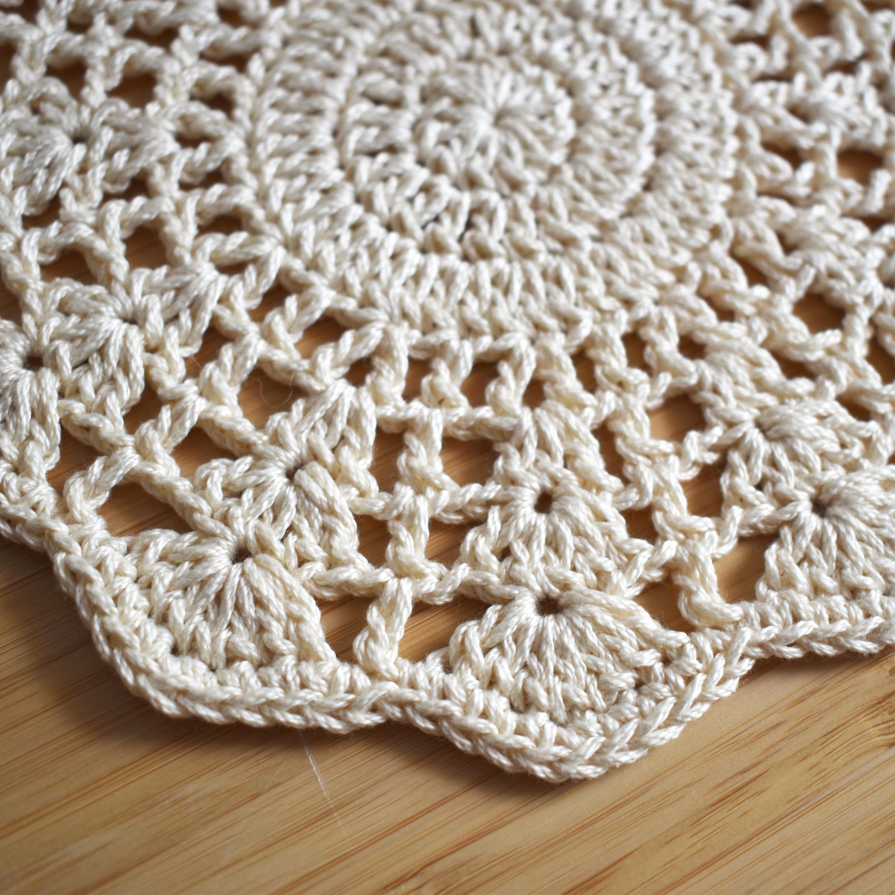 Close-up of a crocheted floral doily on a wooden surface.