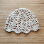 Beige crocheted hat on a wooden surface.