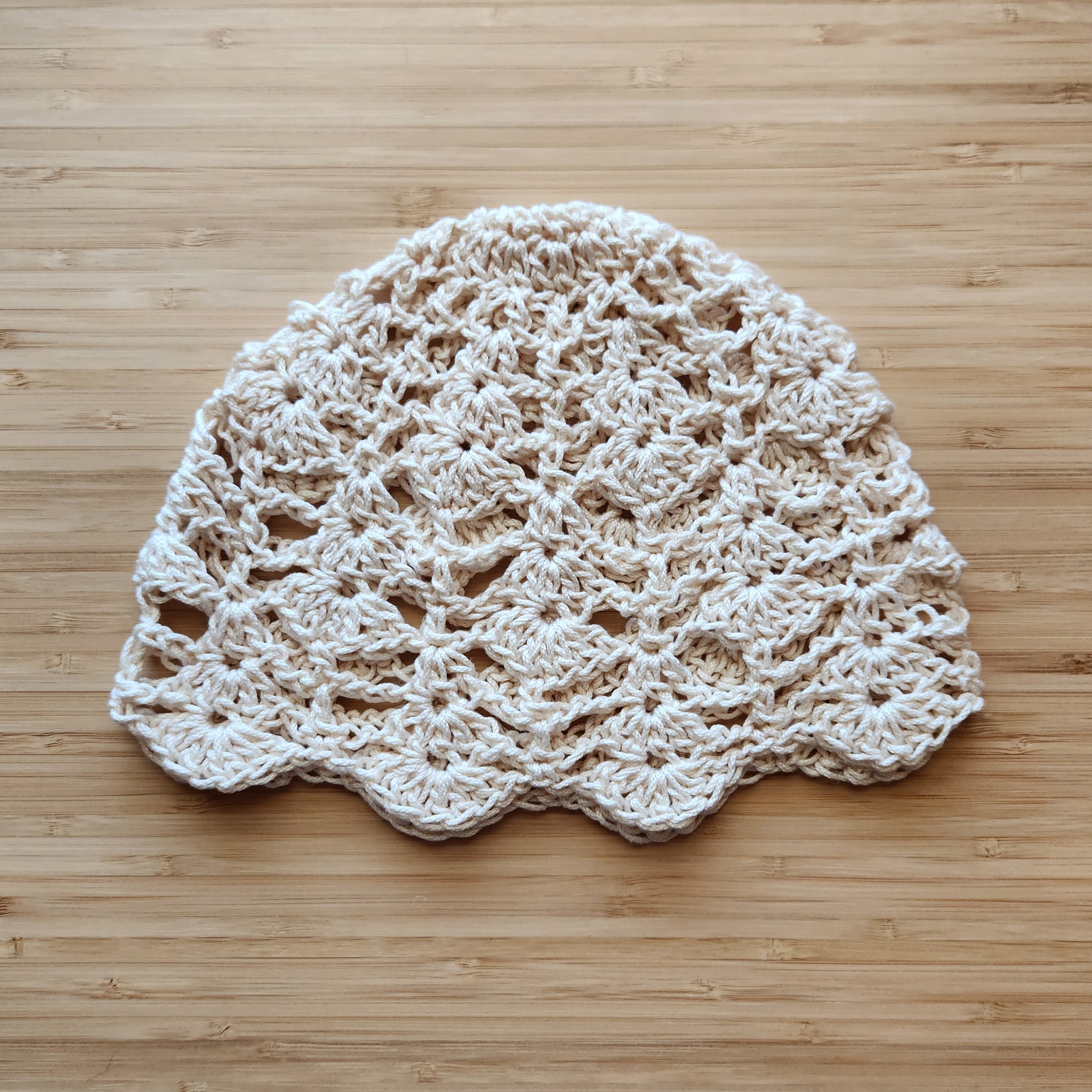 Beige crocheted hat on a wooden surface.