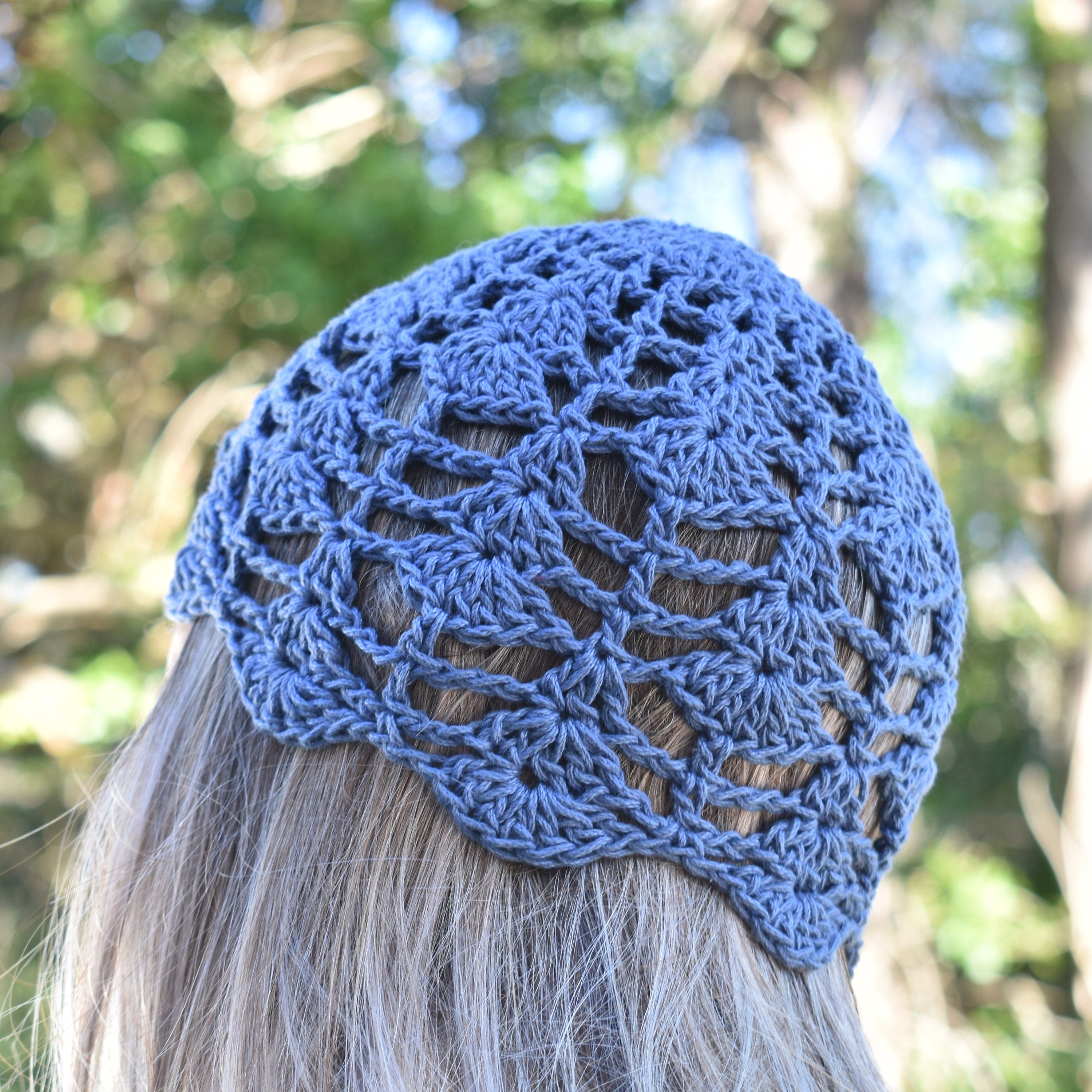 A woman wearing a blue lace skull cap looking into a blurred natural outdoor background.