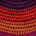 Close-up of a multicolored knitted fabric with a purple, red, and orange striped pattern.