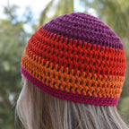Colorful striped beanie worn by a person looking into a blurred natural outdoor background.