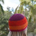 Person wearing a colorful striped beanie with trees in the background.
