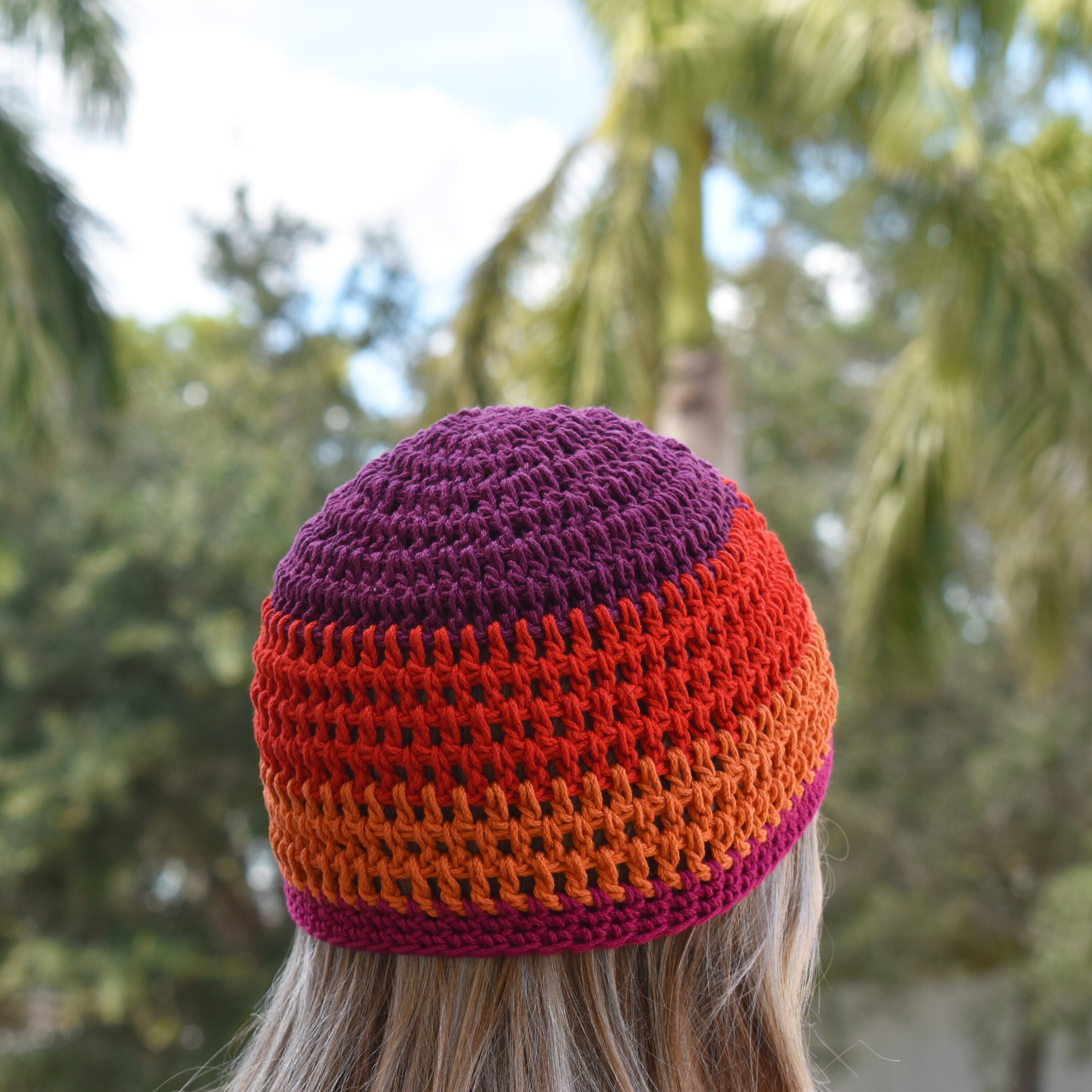 Person wearing a colorful striped beanie with trees in the background.