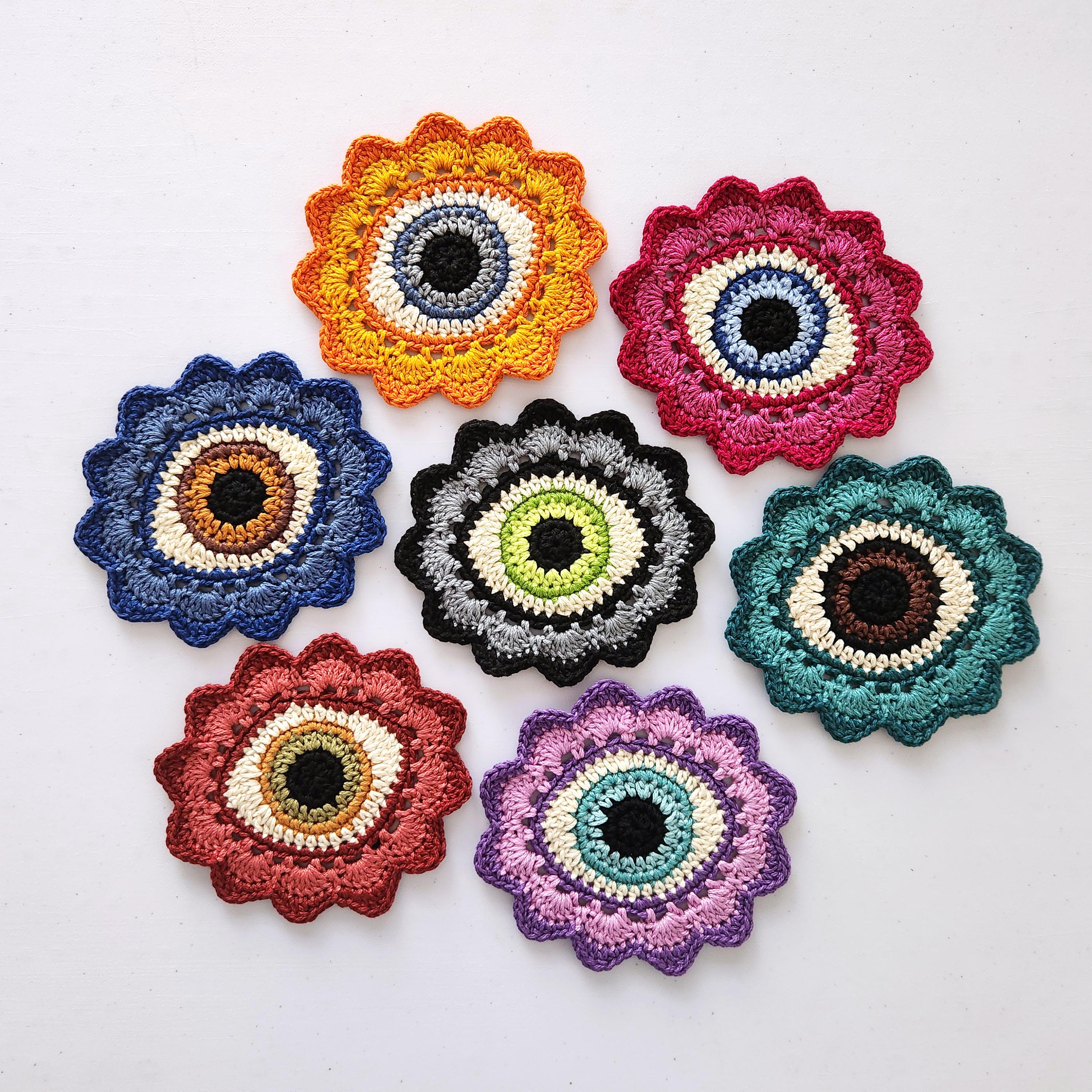 Set of colorful crocheted flowers with eye centers on a white background.