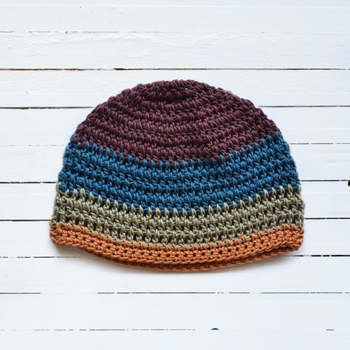 Multicolored striped beanie on a white wooden surface.