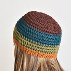 Multicolored striped beanie worn by a person against a neutral background.