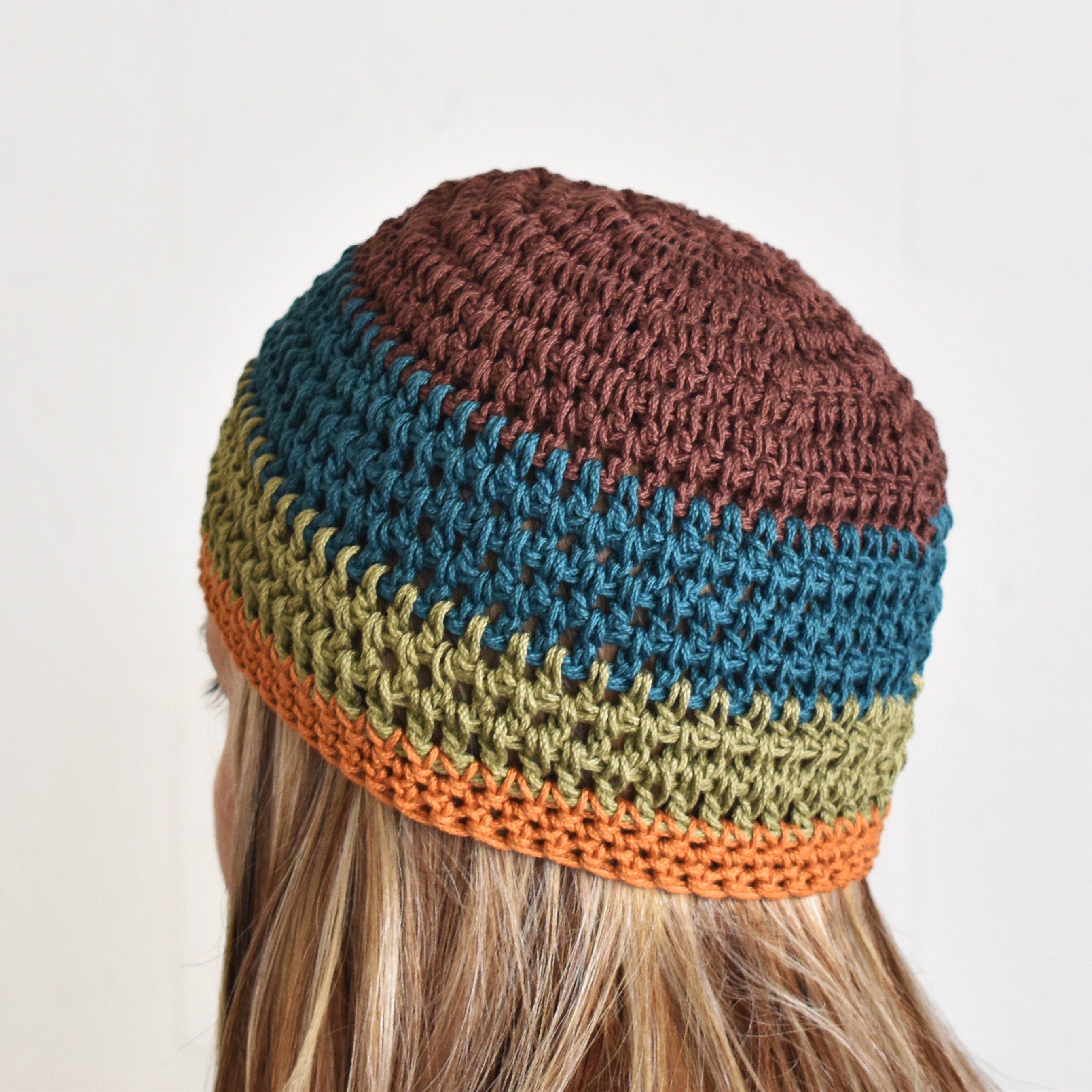 Multicolored striped beanie worn by a person against a neutral background.
