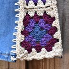 Close-up view of a granny square attached to denim jeans.