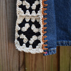 Close-up of a black-and-white granny square insert on jeans.