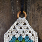 Crocheted wall hanging with a wooden ring on an old wooden fence.