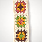 Crocheted granny square wall hanging on a white background.