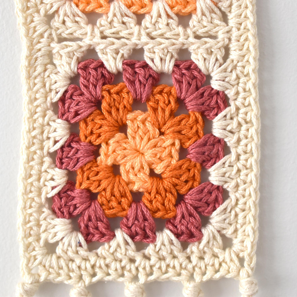 Crocheted square with a colorful granny square pattern on a white background.