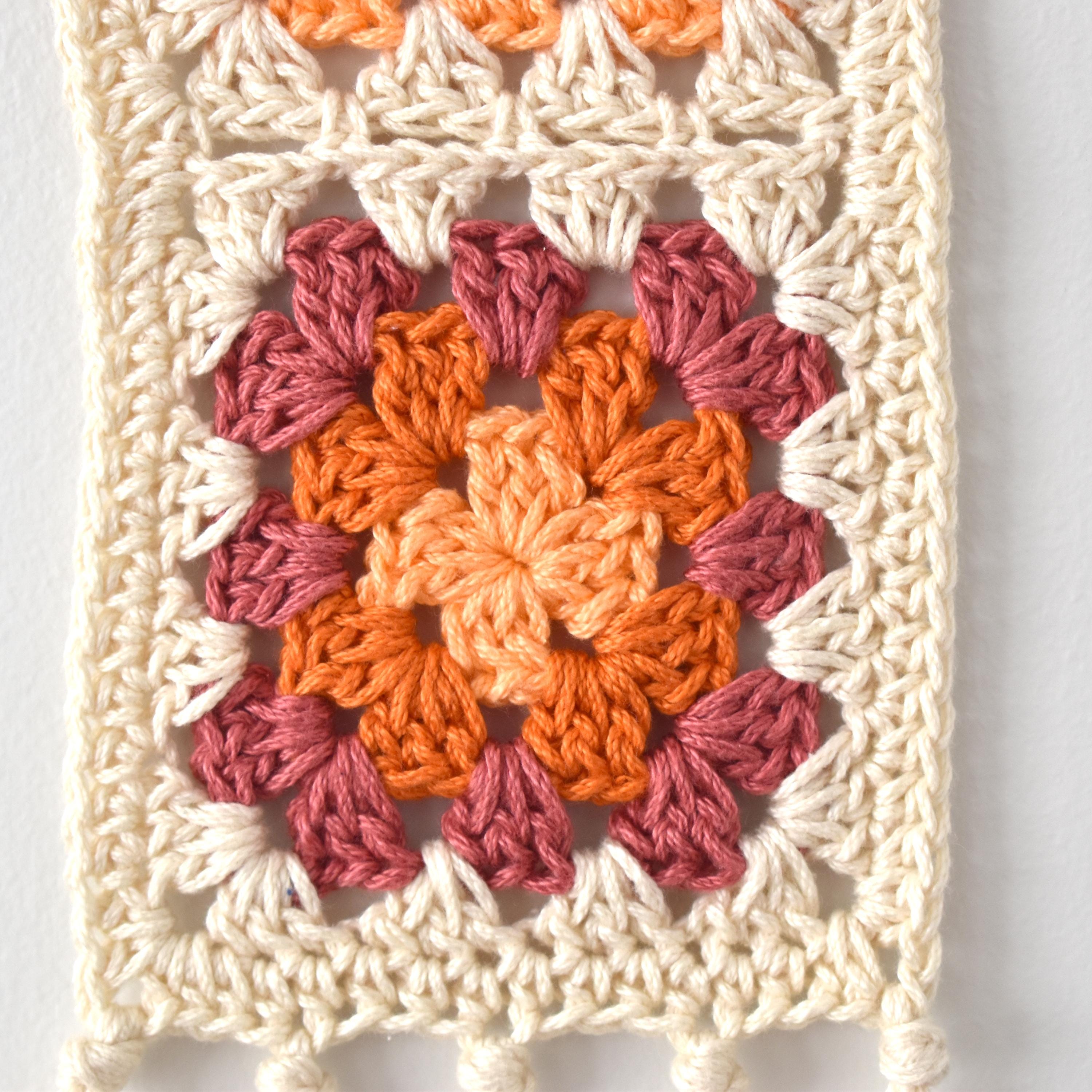 Crocheted square with a colorful granny square pattern on a white background.