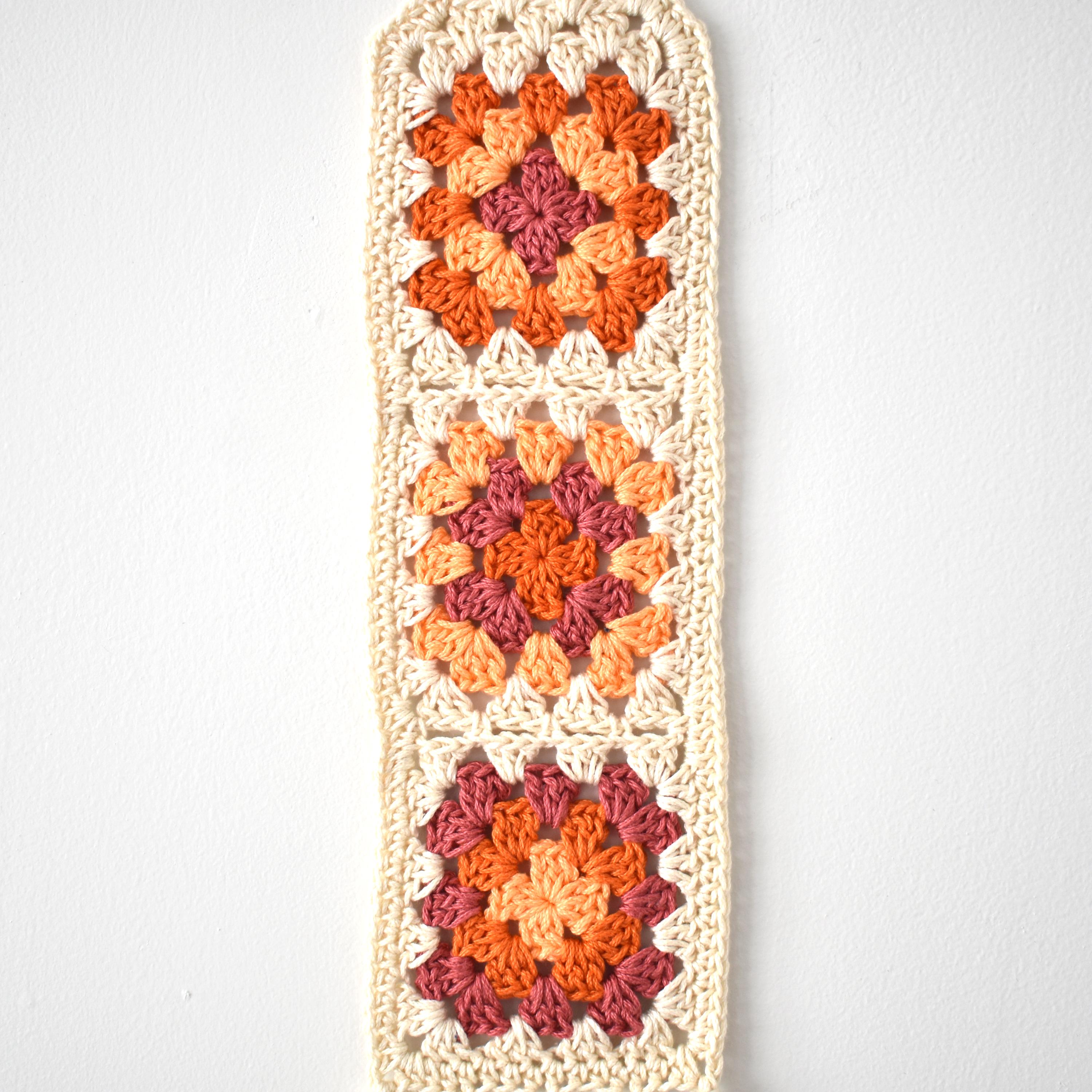 Crocheted wall hanging with a geometric pattern on a white background.