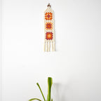 Crocheted wall hanging with geometric pattern on a white background.