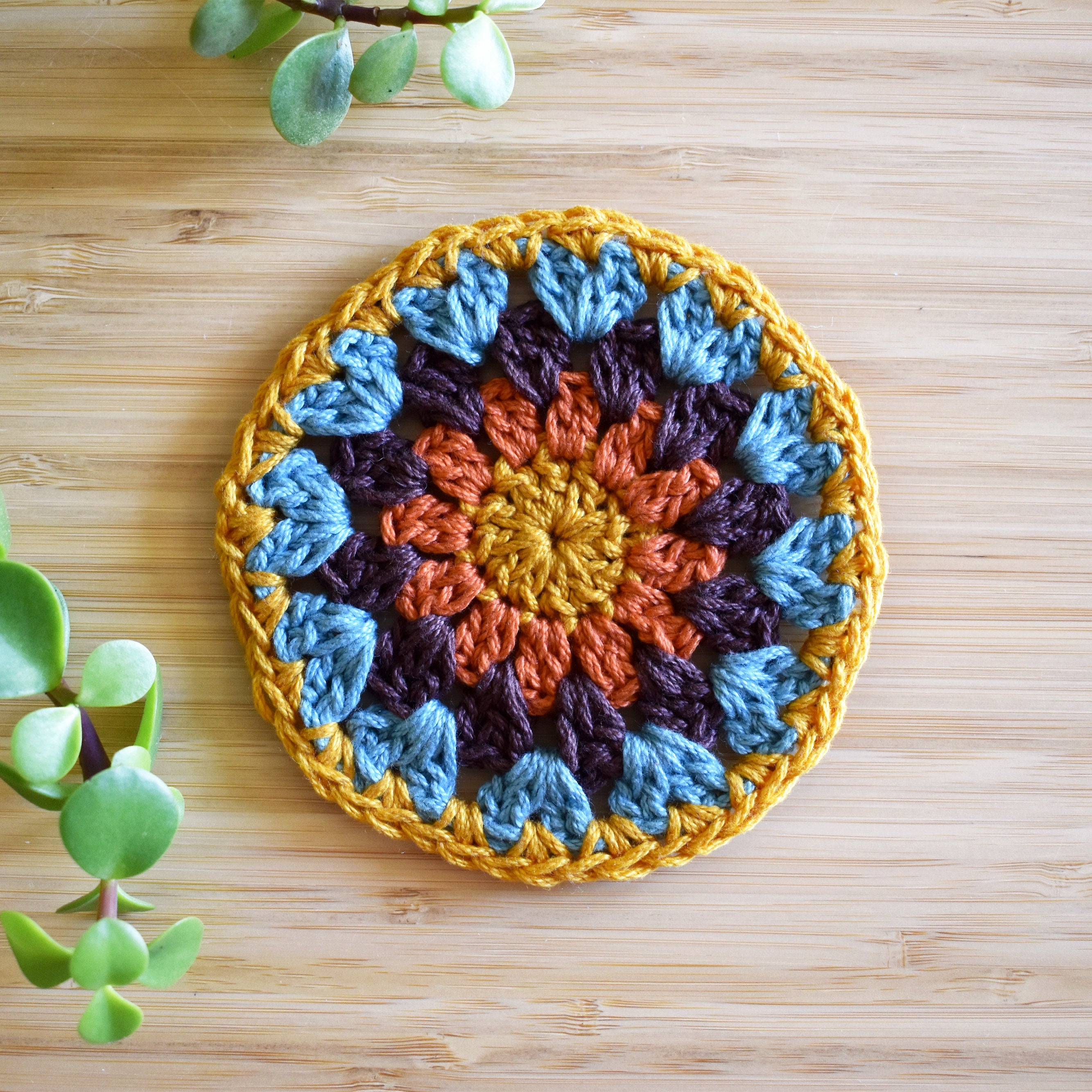 Round crocheted coaster with a colorful pattern on a wooden surface.