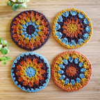 Four colorful crocheted coasters on a wooden surface.