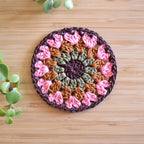 Crocheted coaster with a floral pattern on a wooden surface.