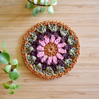 Crocheted coaster with a floral pattern on a wooden surface.