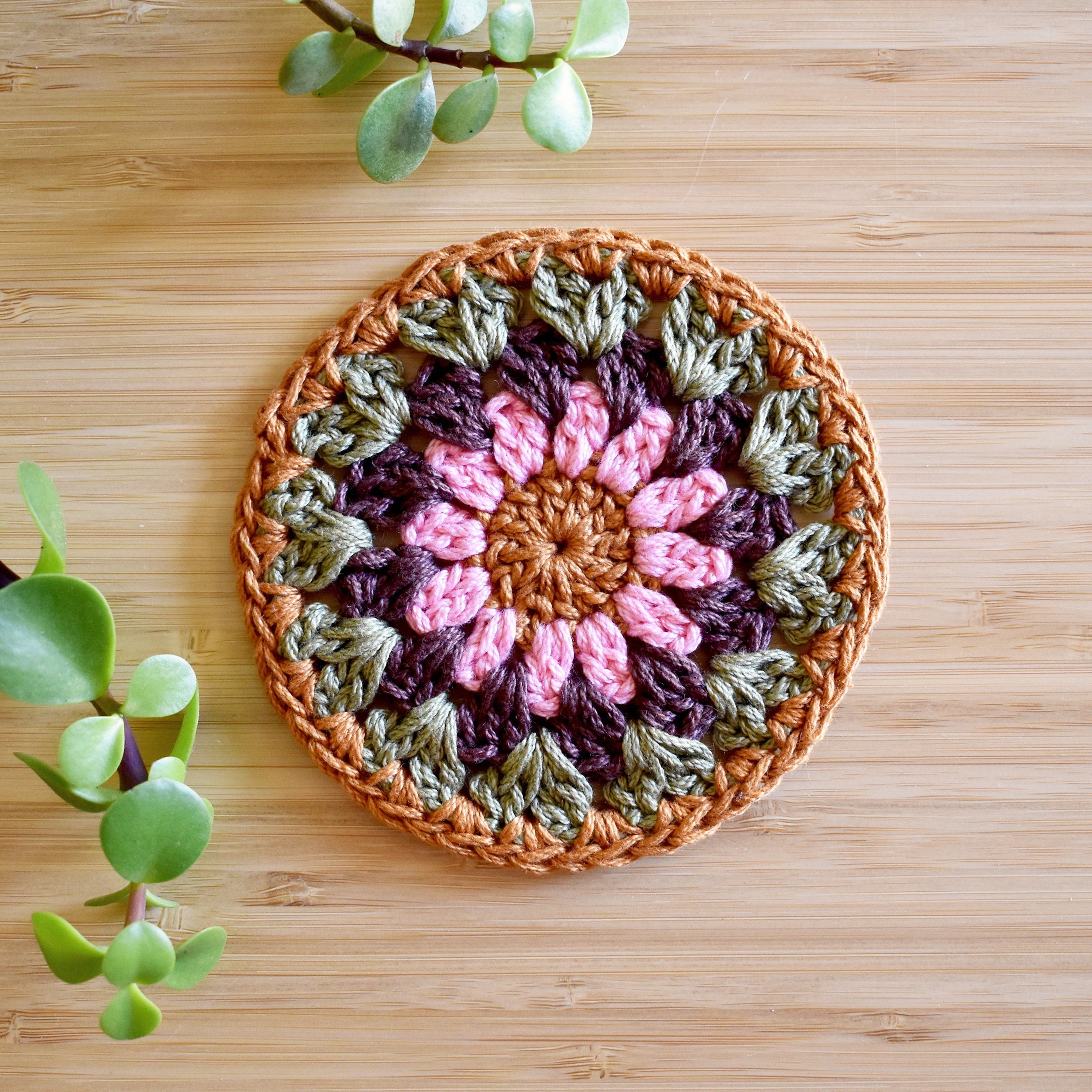 Crocheted coaster with a floral pattern on a wooden surface.
