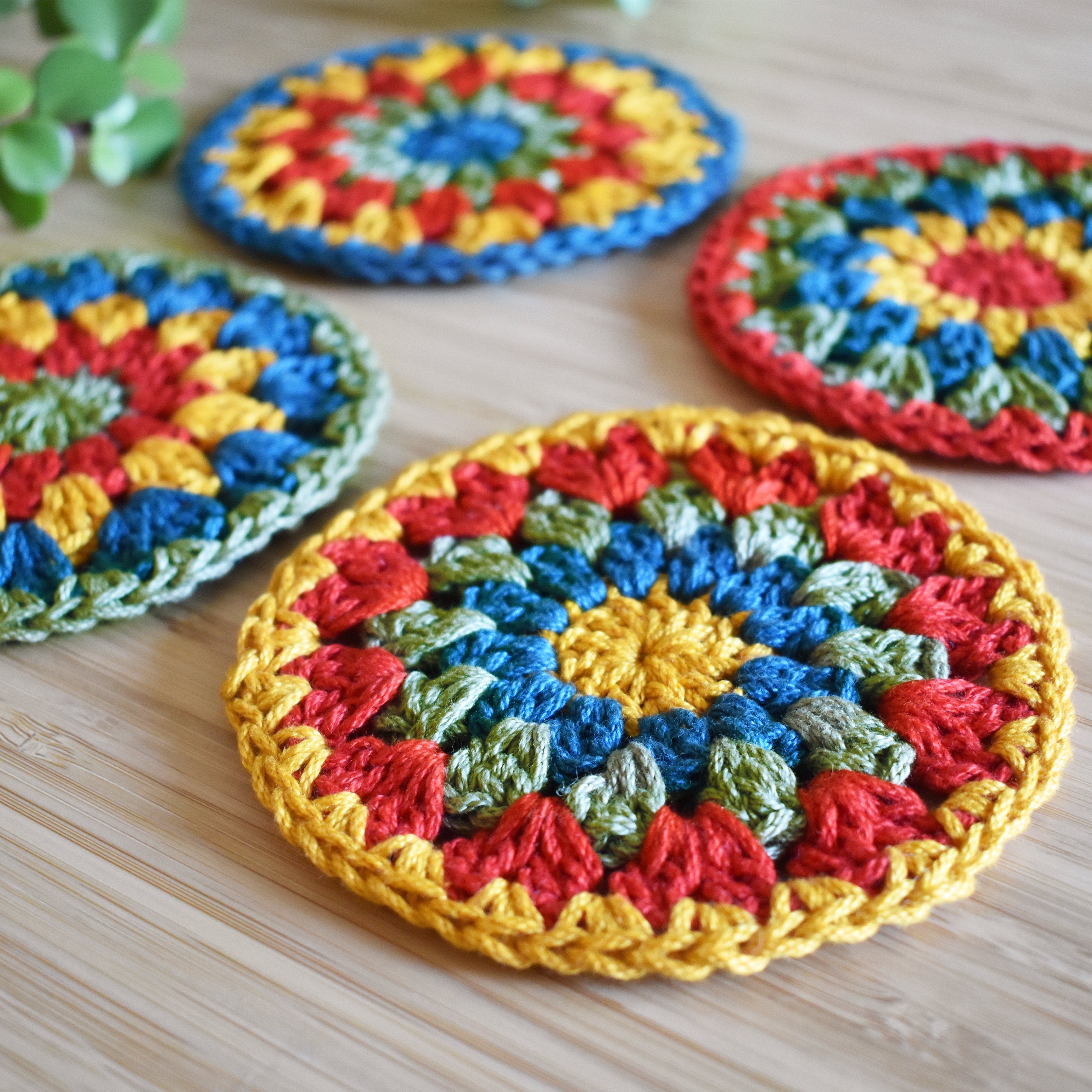 Close-up view of colorful crocheted coasters on a wooden surface.