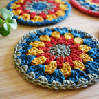 Close-up view of a colorful crocheted coaster on a wooden surface.
