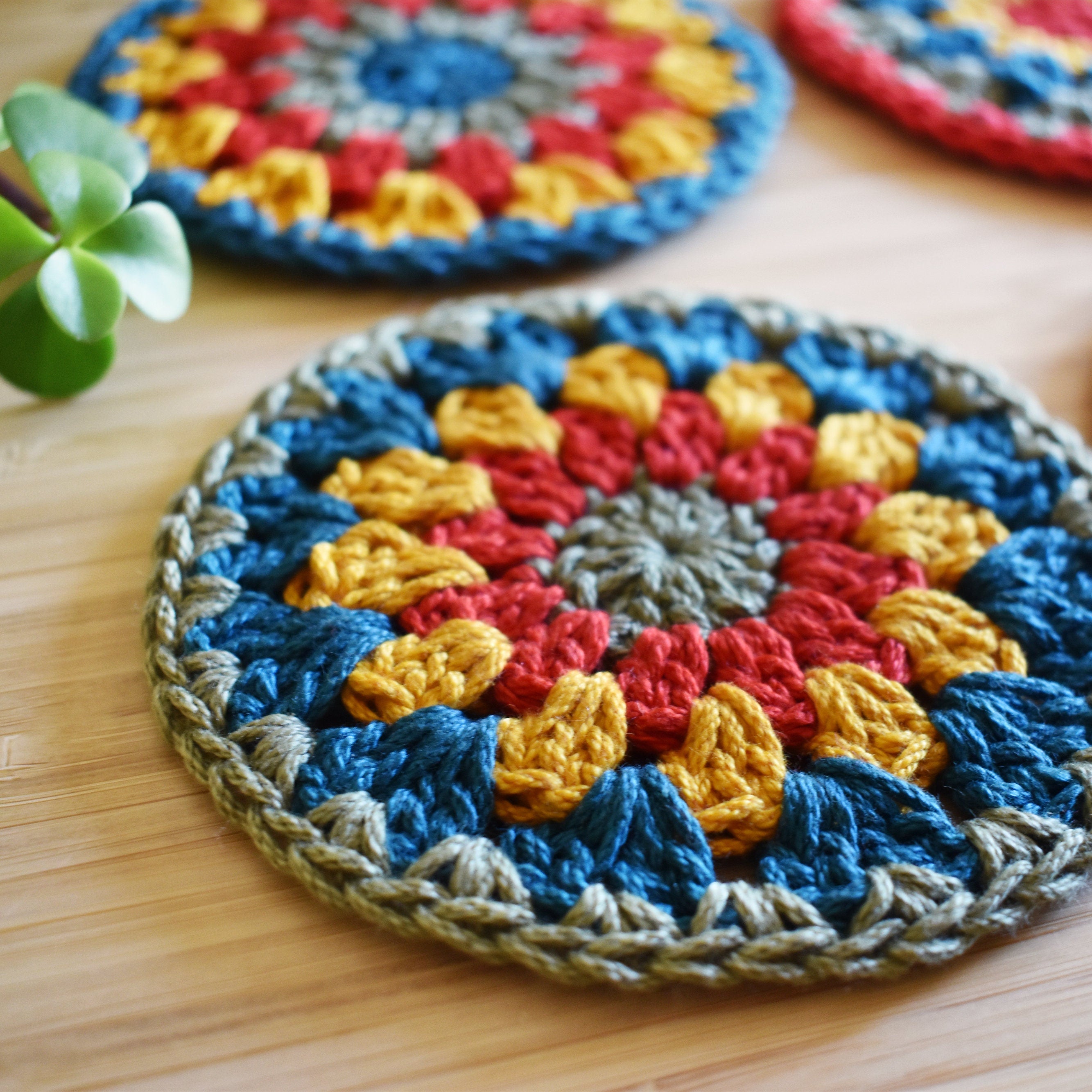 Close-up view of a colorful crocheted coaster on a wooden surface.