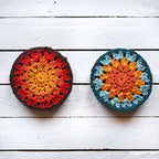 Two crocheted coasters with granny sunburst patterns on a white painted wooden surface.