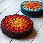 Two stacks of crocheted coasters with a granny sunburst color pattern on a wooden surface.