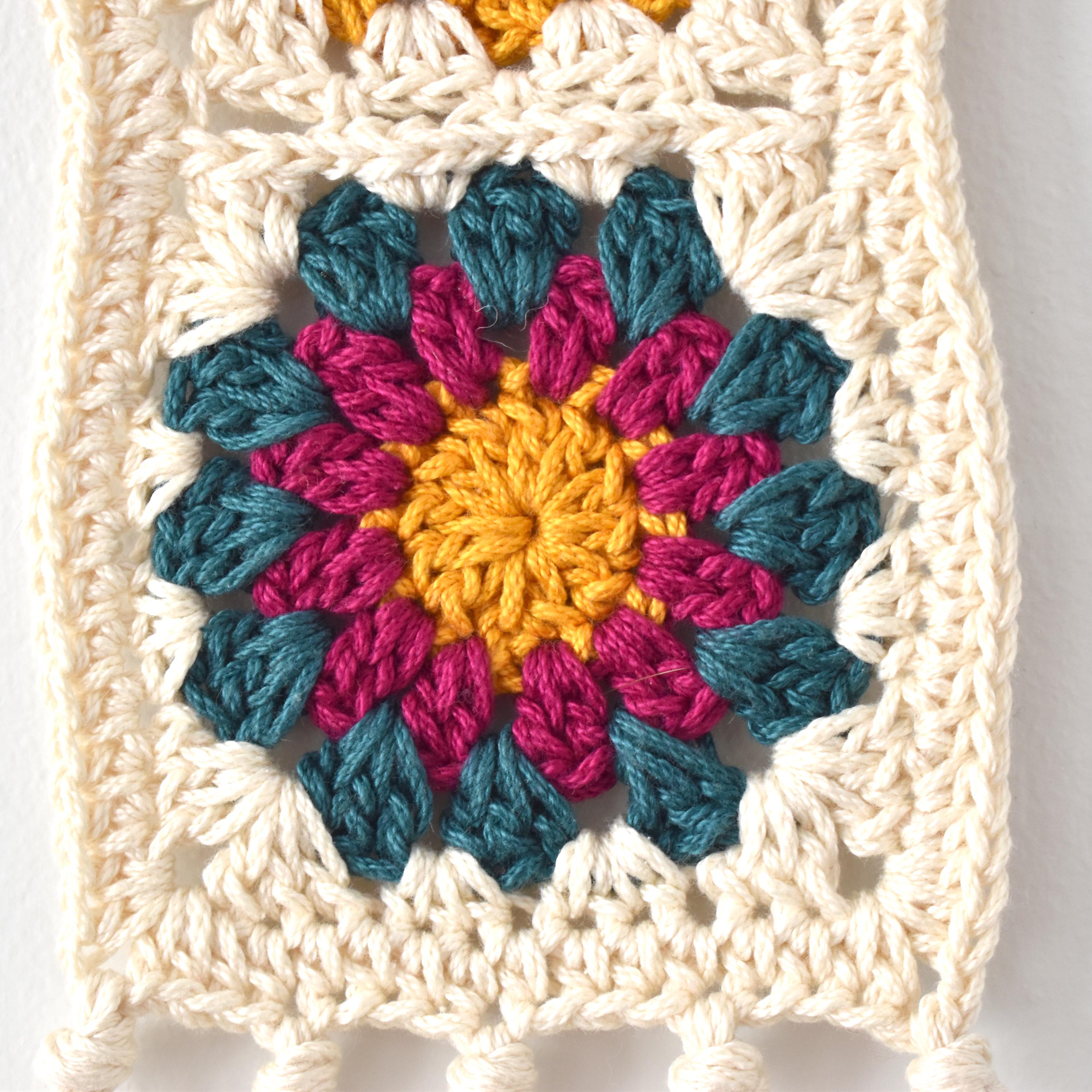 Colorful crocheted flower pattern on a white background.