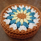 Stack of crocheted coasters with a colorful sunflower pattern on a wooden surface.