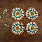 Four crocheted coasters with a floral pattern on a wooden surface.