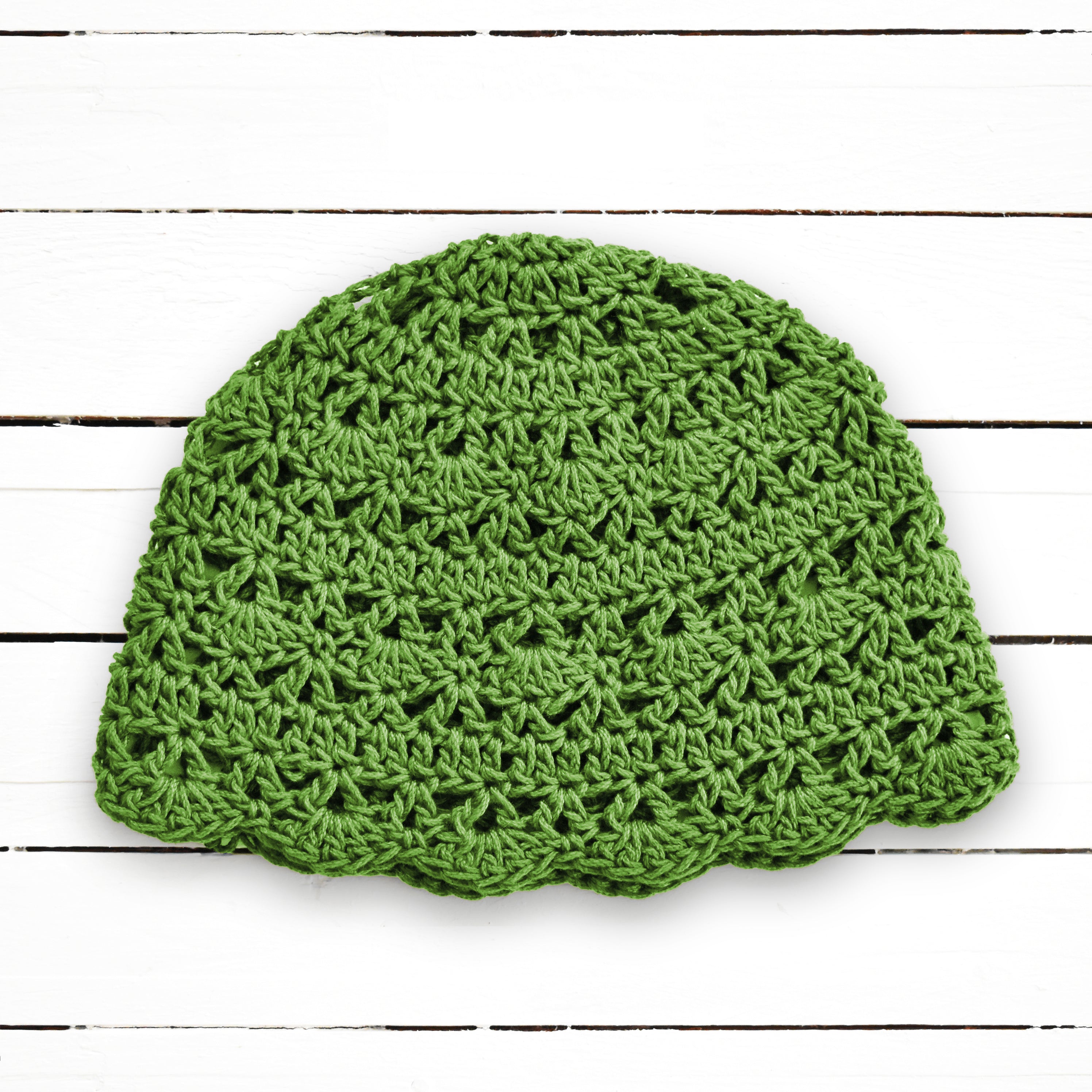Green crochet beanie on a wooden surface.