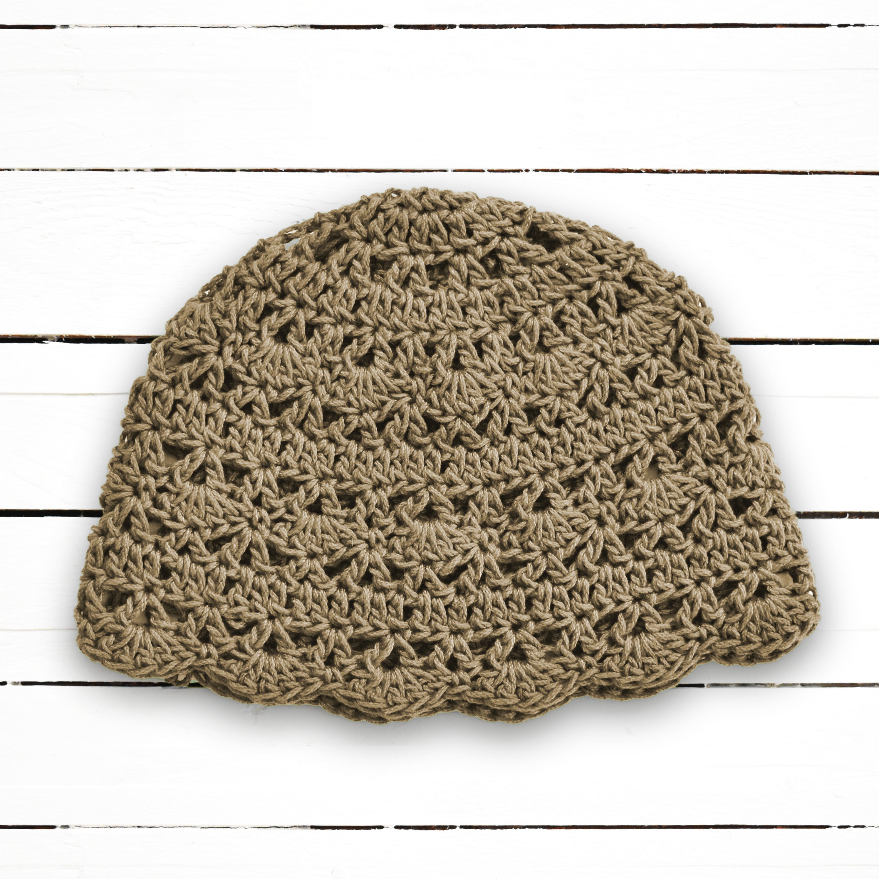 Tan crochet beanie on a wooden surface.
