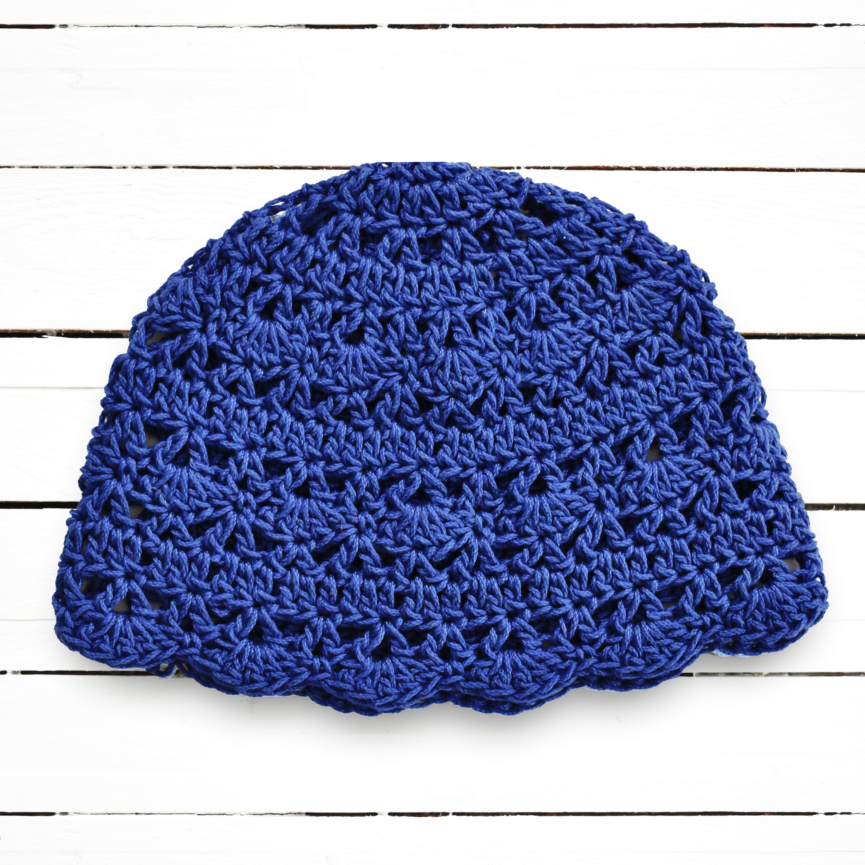 Blue crocheted beanie on a wooden surface.