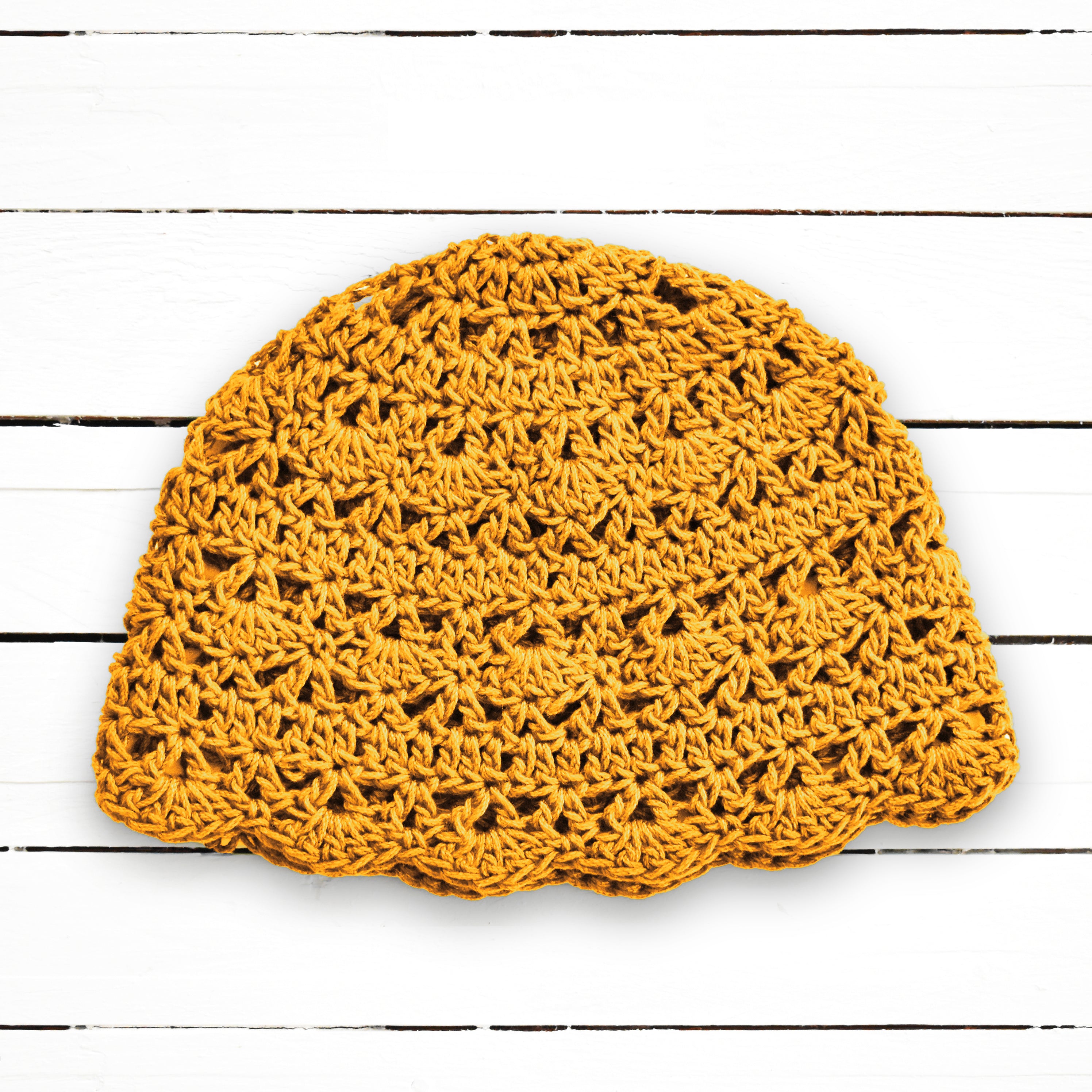 Yellow crochet hat on a wooden surface.