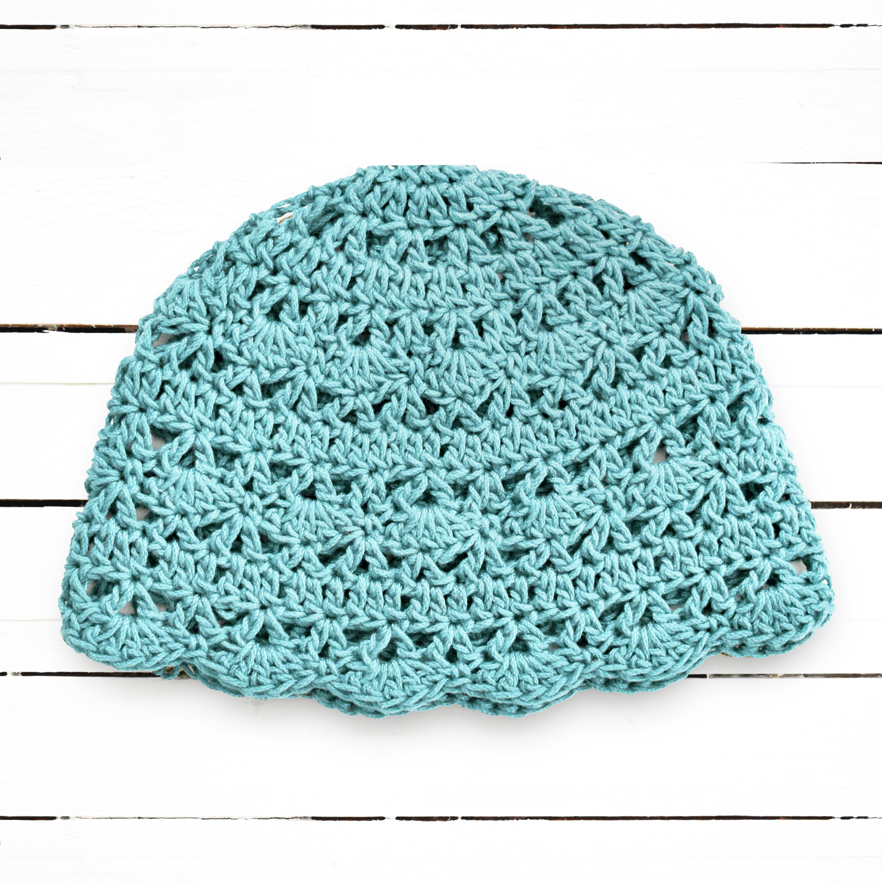 Light blue crocheted beanie on a wooden surface.