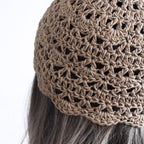 Close-up of a light brown knitted hat on a person with gray hair.